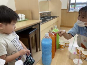 🍹ジュース屋さんごっこ🍹」 赤・青・黄・白の色水を混ぜて、色とりどりのジュースを作りました✨ 「この色はぶどうジュース ！」「こっちはレモン！」と、できた色から想像を膨らませ、自分だけのオリジナルジュースが完成🍇🍋 最後は、実際にカルピスの原液と水を混ぜて